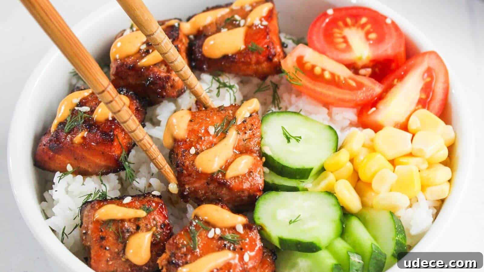 28 Seafood Dinners for Two That Deliver Restaurant-Quality Flavor 7 A bowl of white rice topped with glazed salmon, sliced cucumbers, corn, tomato wedges, and a drizzle of orange sauce, with chopsticks picking up a piece of salmon.