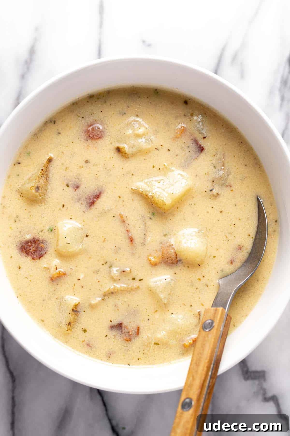 Bowl of loaded baked potato soup with a spoon in it. 