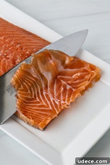 Homemade Gravlax: Simple Cured Salmon with Dill and Citrus 12 Person cutting through cured salmon with a knife.