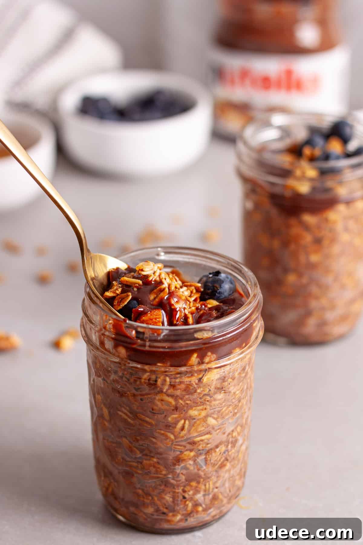 Nutella Overnight Oats Recipe for Creamy Chocolate Breakfast 11 A spoon in a small mason jar of Nutella overnight oats on a gray table.