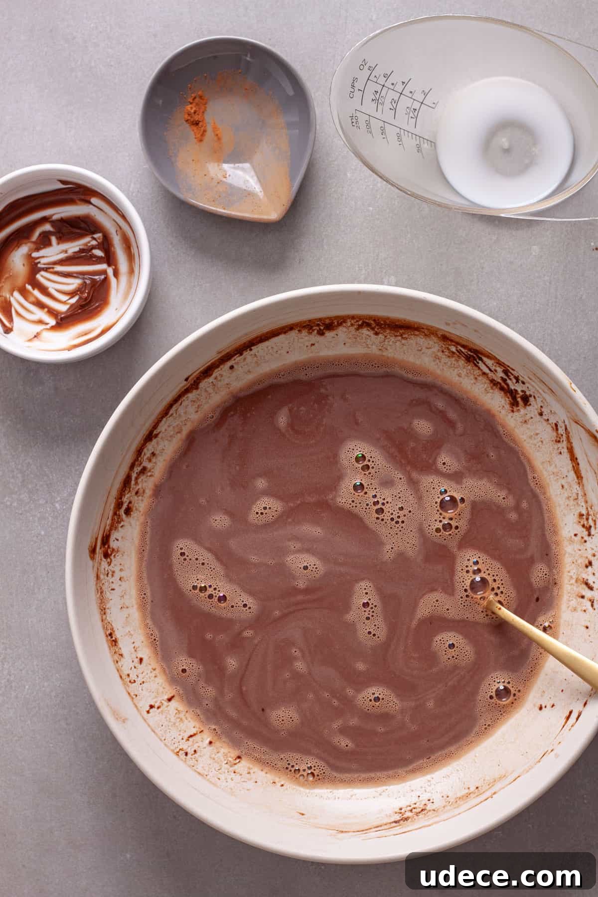 Nutella Overnight Oats Recipe for Creamy Chocolate Breakfast 4 Milk, cocoa powder and nutella getting stirred together in a white mixing bowl.