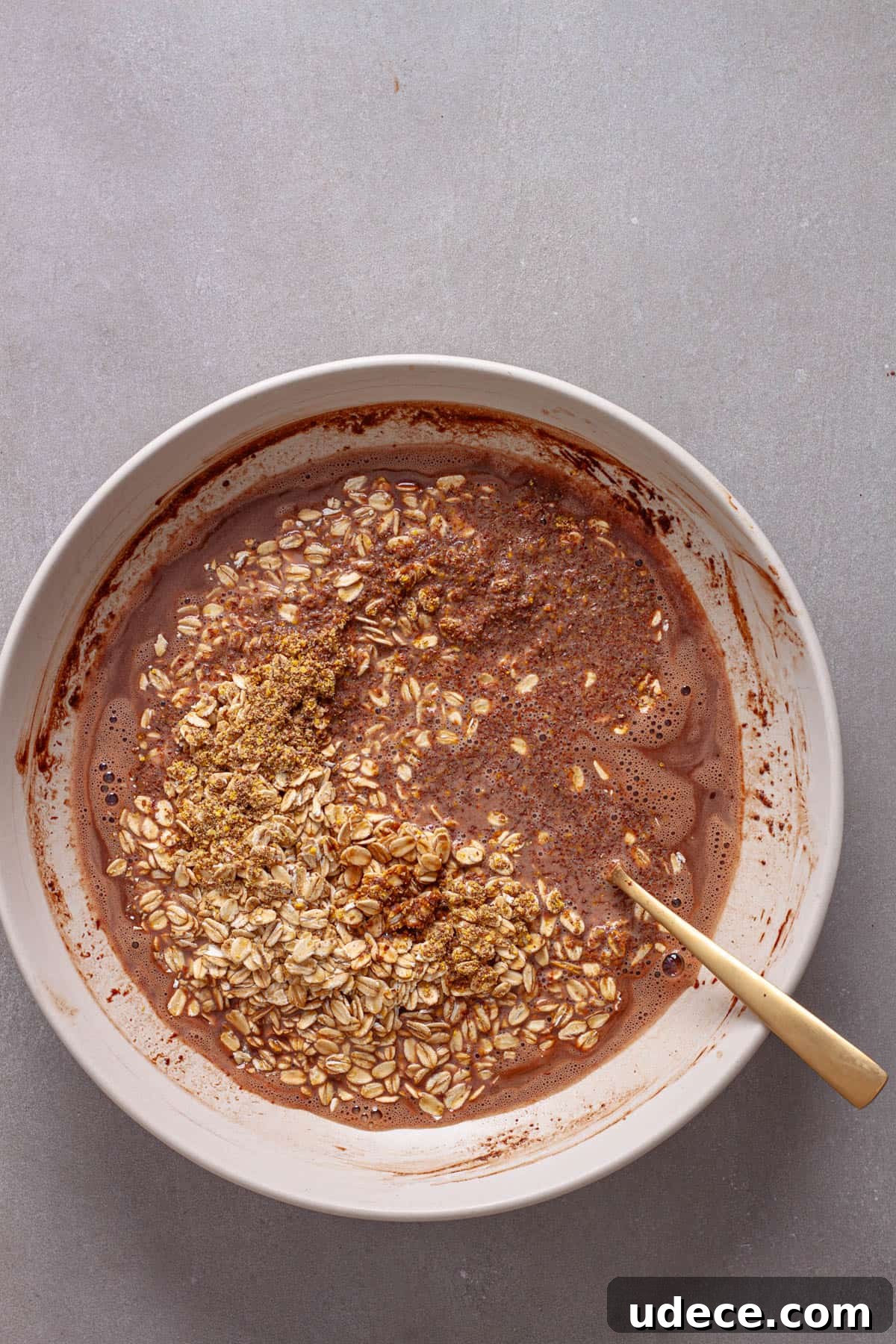 Nutella Overnight Oats Recipe for Creamy Chocolate Breakfast 5 Milk and nutella in a mixing bowl with rolled oats and flaxseeds getting stirred in.