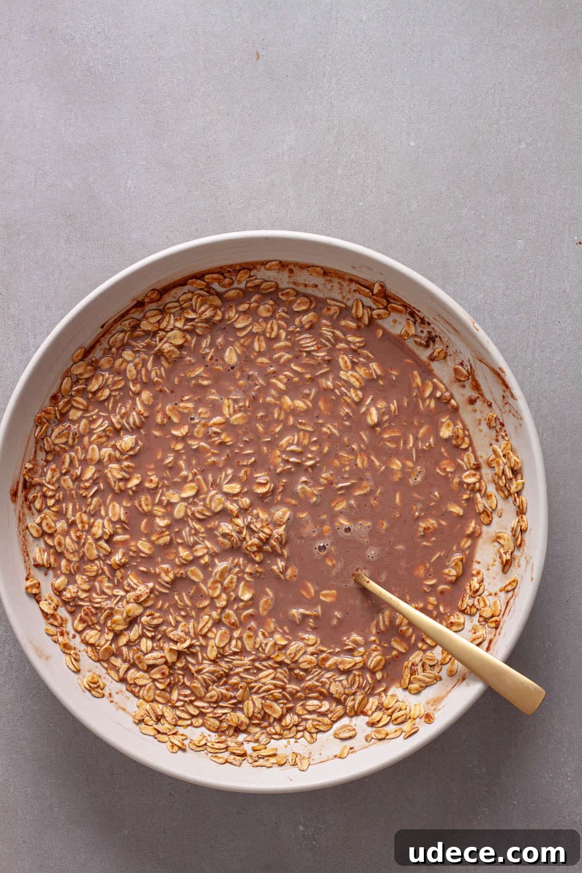Nutella Overnight Oats Recipe for Creamy Chocolate Breakfast 6 Rolled oats soaking in a chocolate milk mixture in a white bowl.
