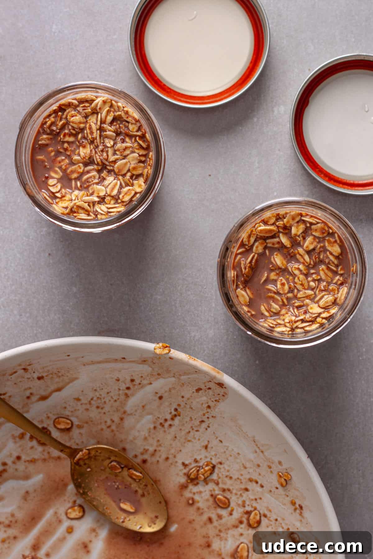 Nutella Overnight Oats Recipe for Creamy Chocolate Breakfast 7 Oats and chocolate milk getting added to small mason jars for Nutella overnight oats.