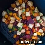 Roasted root vegetables garnished with fresh parsley in the air fryer basket.