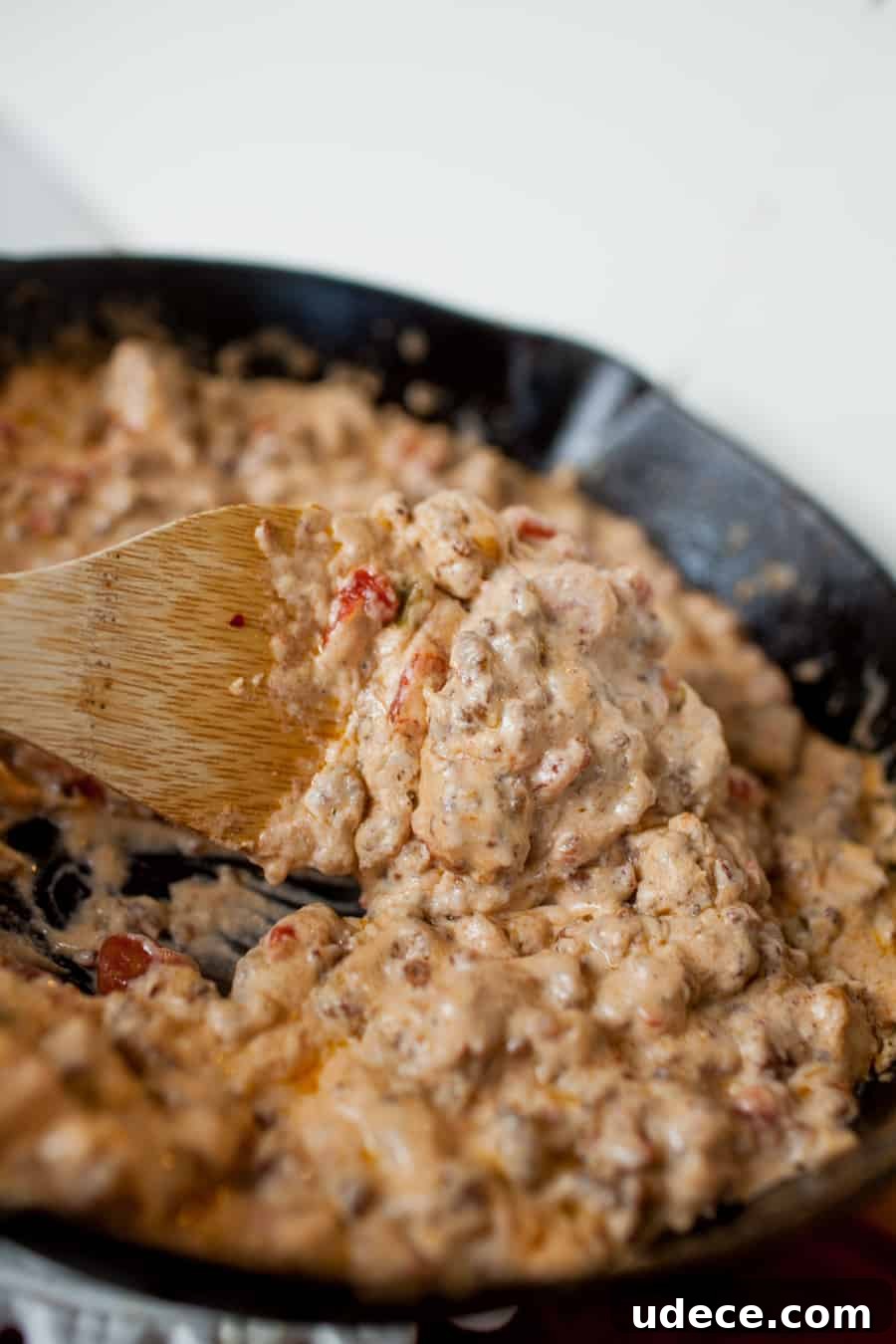 Creamy Skillet Sausage Dip Recipe for Game Day and Parties 7 a wooden spoon stirring skillet sausage dip