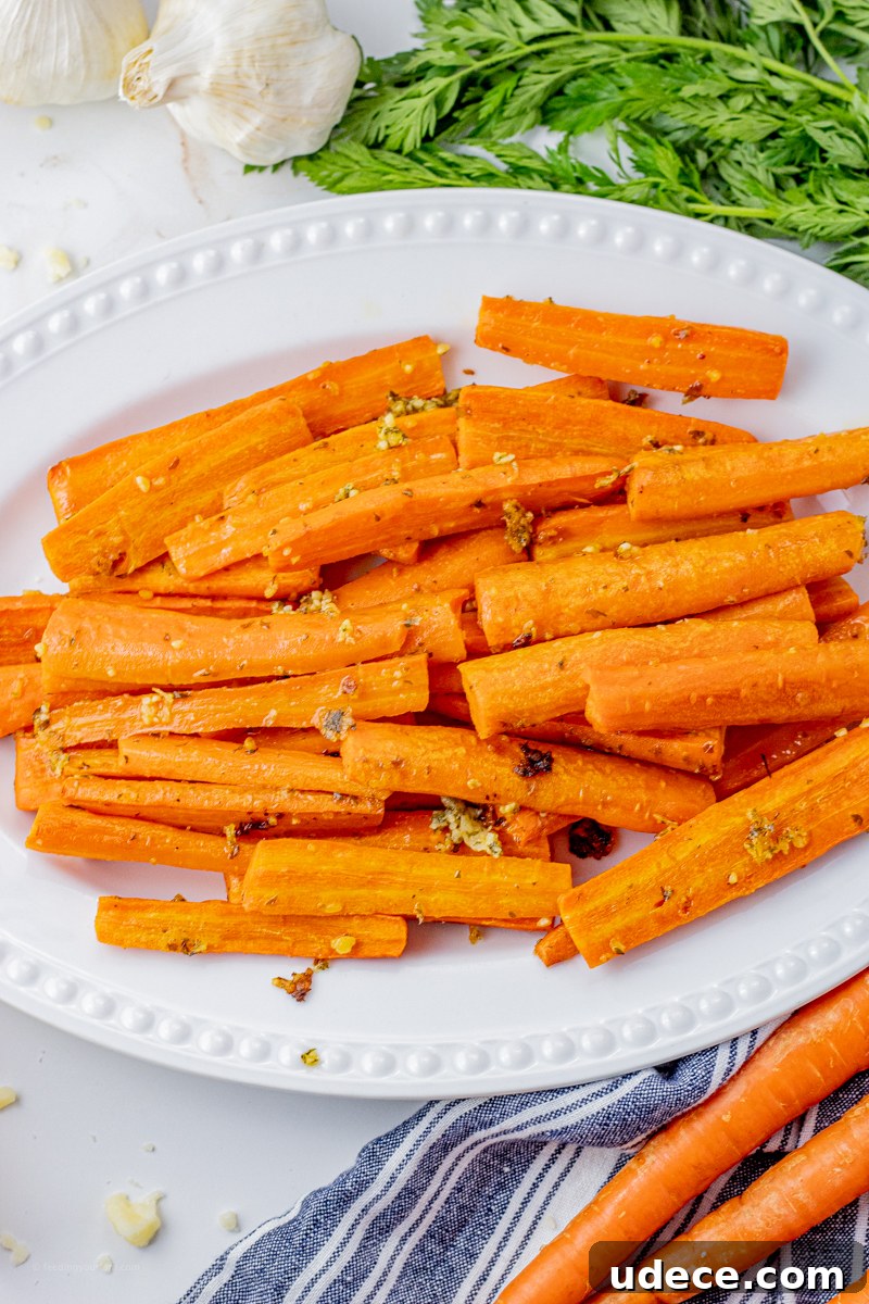 sliced, cooked carrots with garlic and parmesan on a white serving platter