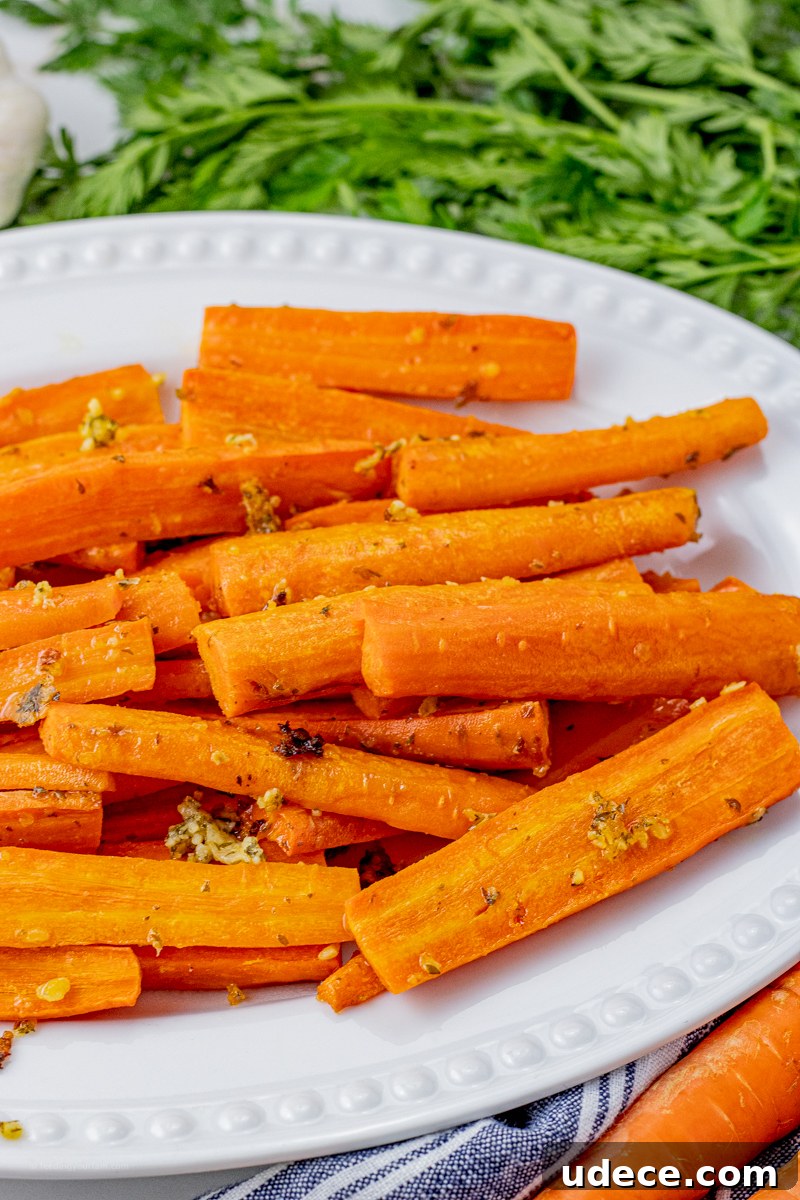 sliced orange carrots with garlic and parmesan pieces on the carrots on a white serving platter