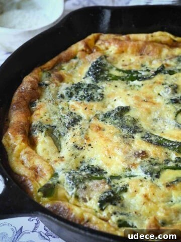 Close-up of broccolini frittata in a skillet with parmesan cheese in the background.