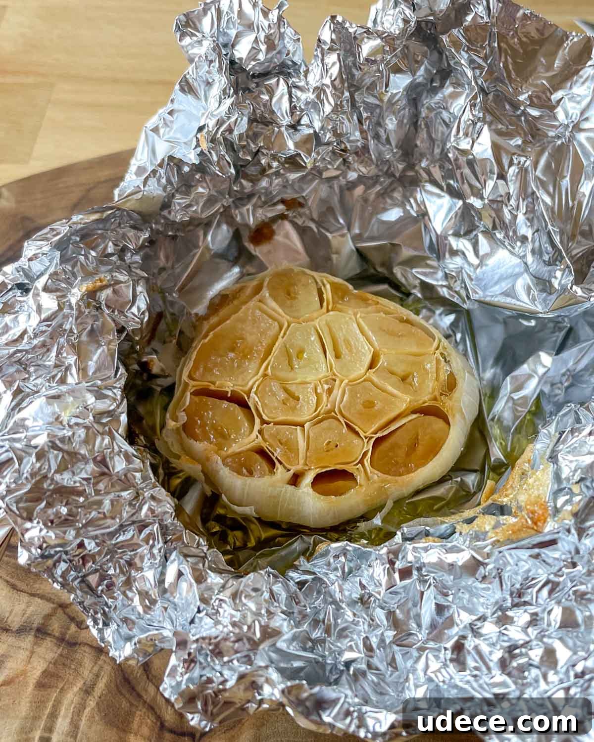How to Roast Garlic Perfectly for Rich, Sweet Flavor 7 A head of roasted garlic sits in tin foil on a wooden cutting board.