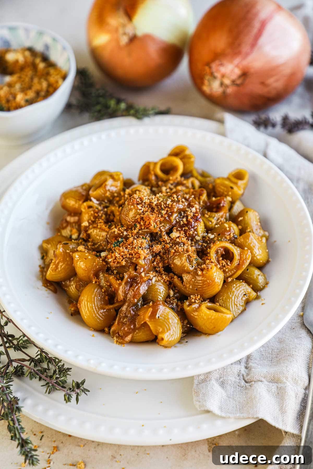 One-pot French onion pasta in a white porcelain bowl made with caramelized onions, gruyere, and herbed pangrattato.