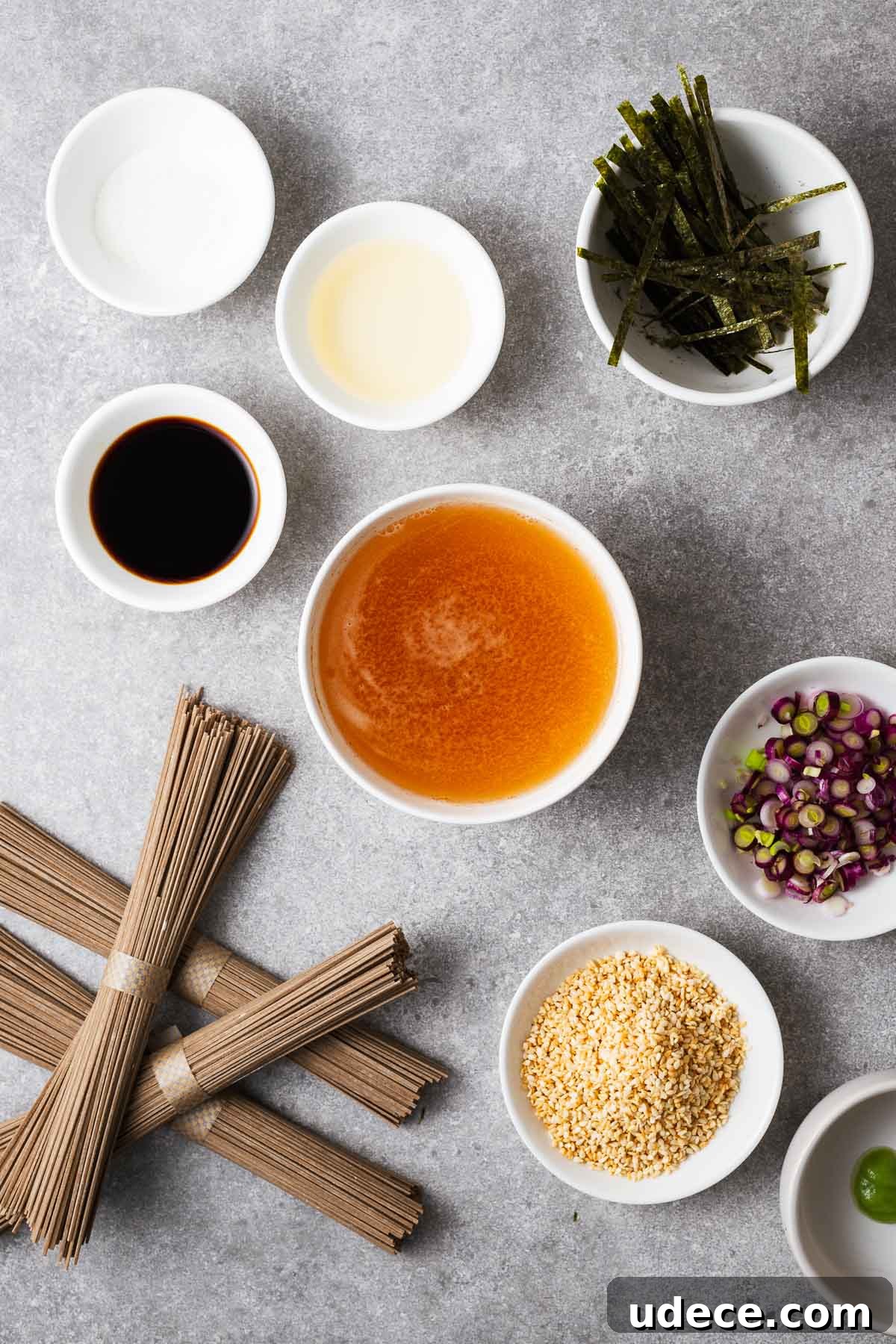 Ingredients for making zaru soba including soba noodles, dashi broth, soy sauce, mirin, sugar and optional toppings.