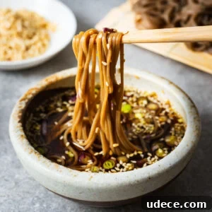 Soba noodles dipped into Japanese mentsuyu dipping sauce with chopsticks.