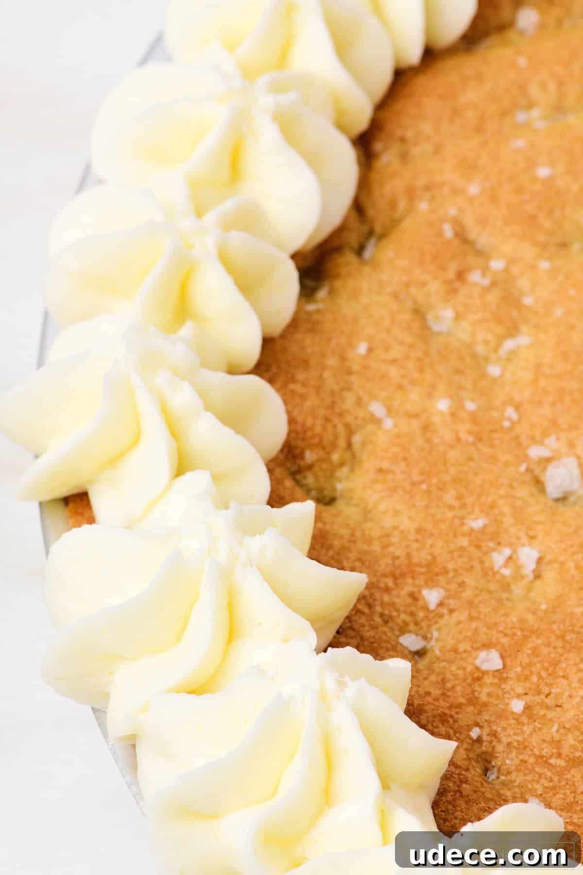 Cookie cake edged with vanilla buttercream frosting and sprinkled with salt flakes.