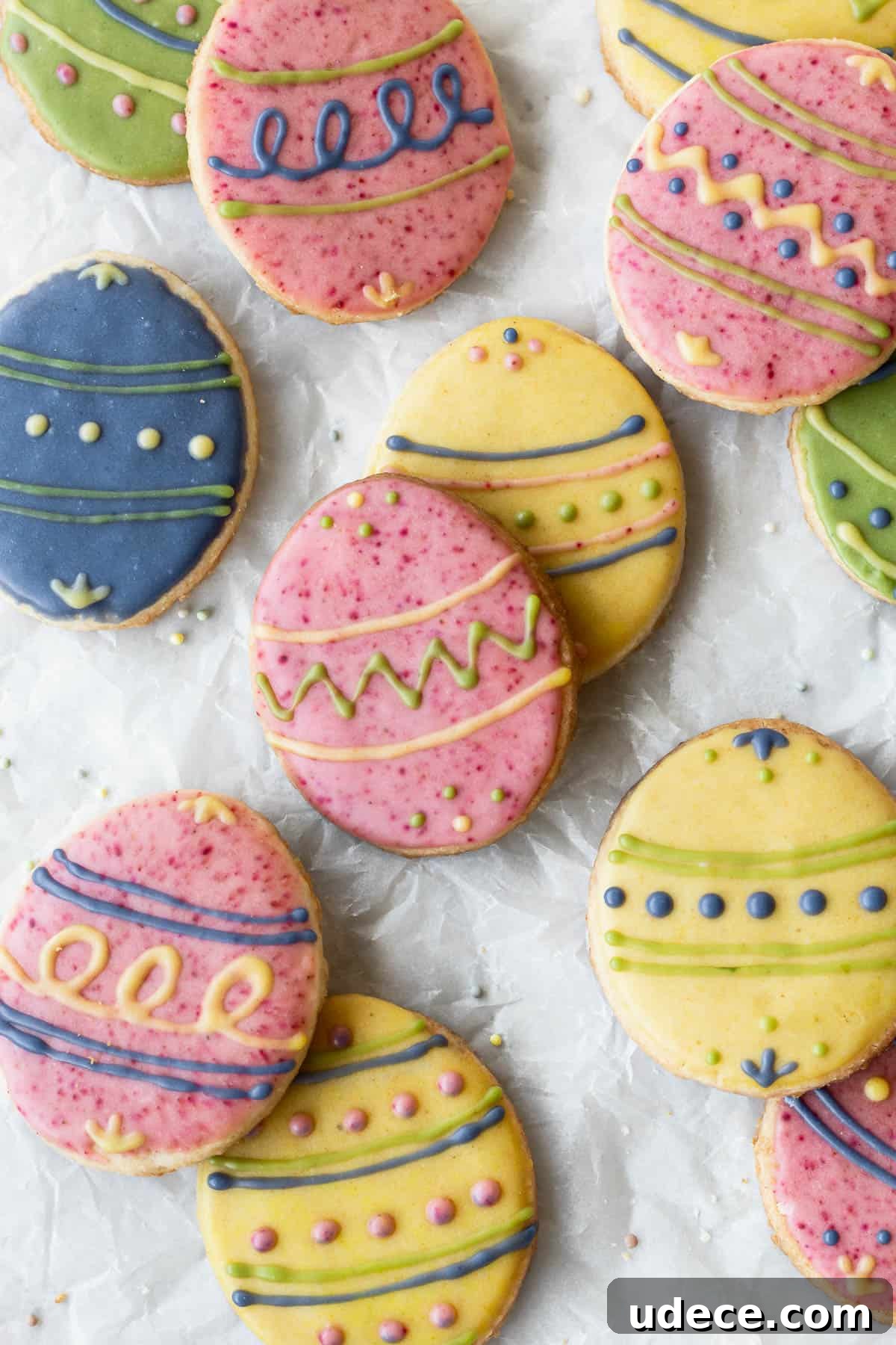 Easter egg sugar cookies decorated with different colored icing on parchment paper.