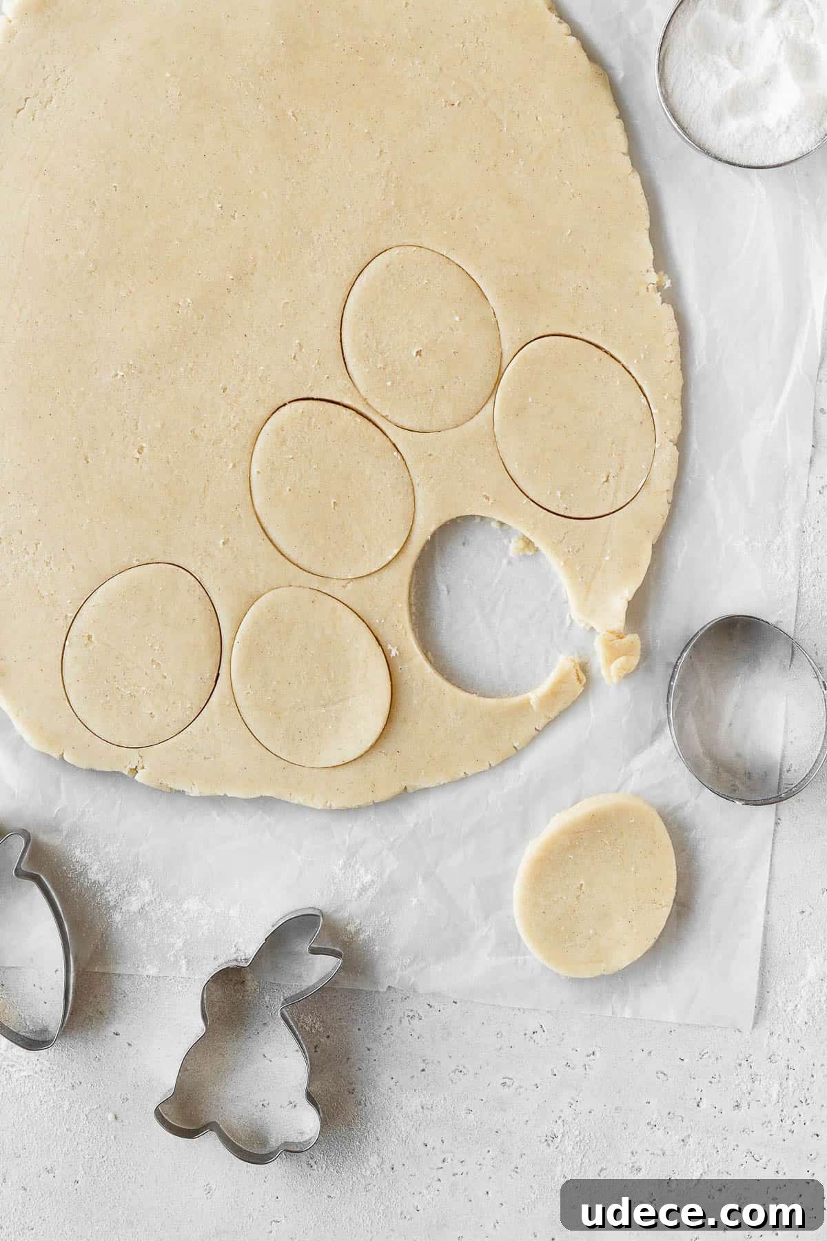 Sugar cookie dough rolled out and shapes being cut with a cookie cutter.