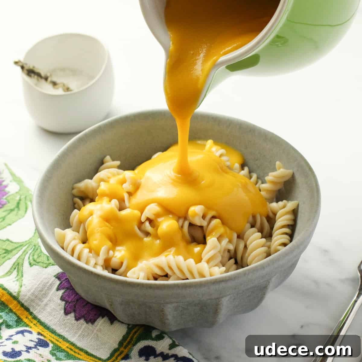 a pale blue bowl of pasta with vegan cheese sauce.