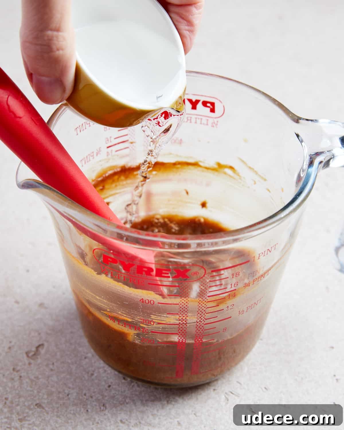 Photo showing water being added to the jug and whisking together to make the satay sauce.