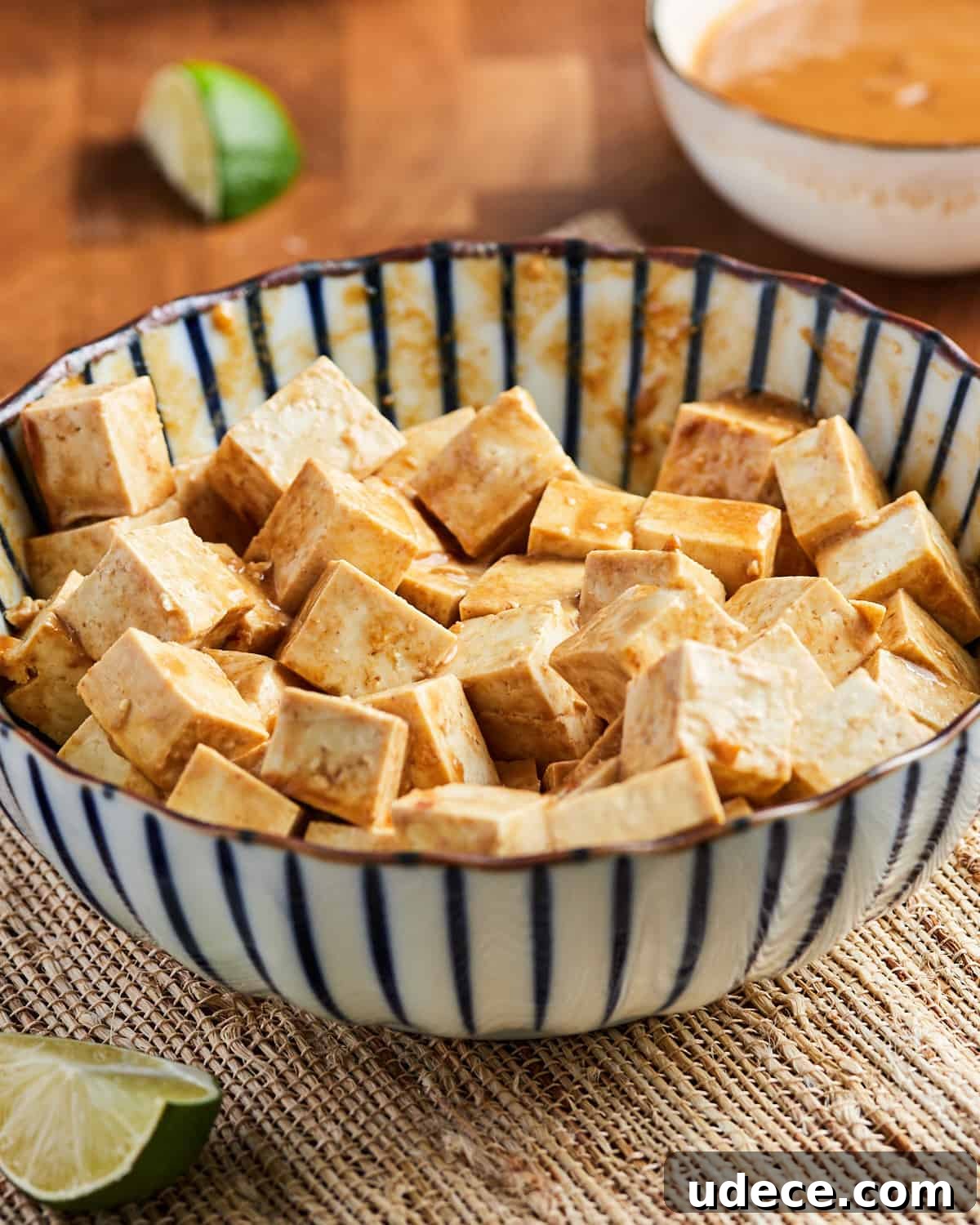 Photo showing a bowl of tofu cubes marinating in Indonesian satay sauce peanut marinade.
