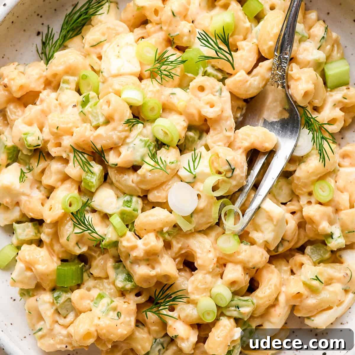 Classic Creamy Macaroni Salad Recipe 5 a fork taking a bite of Macaroni Salad on a plate
