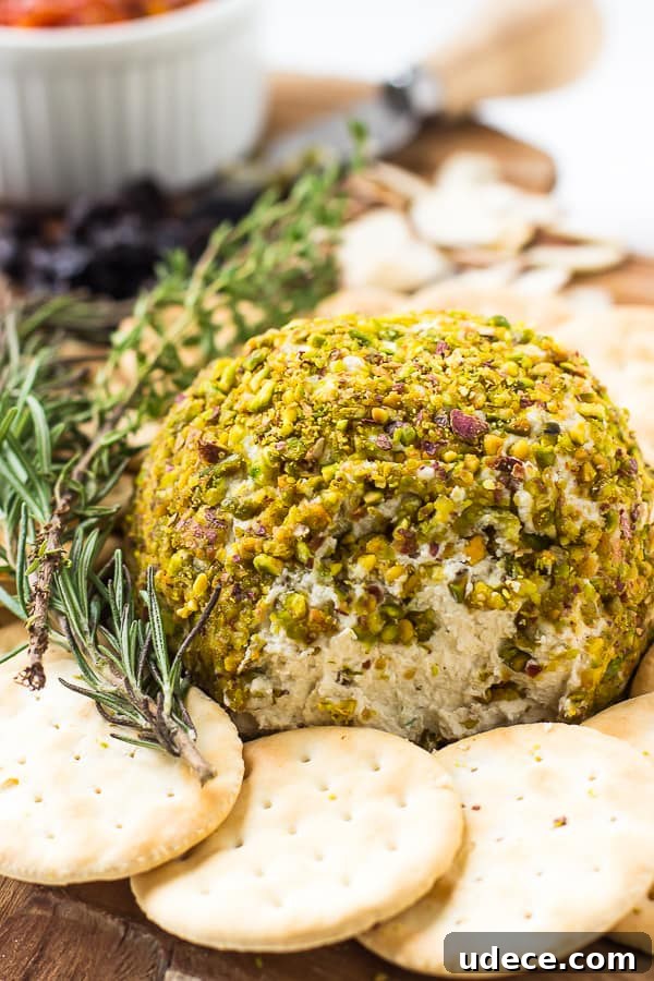 Pistachio-Crusted Vegan Cheese Ball Recipe 2 Pistachio crusted vegan cheese ball on a wood board with crackers.
