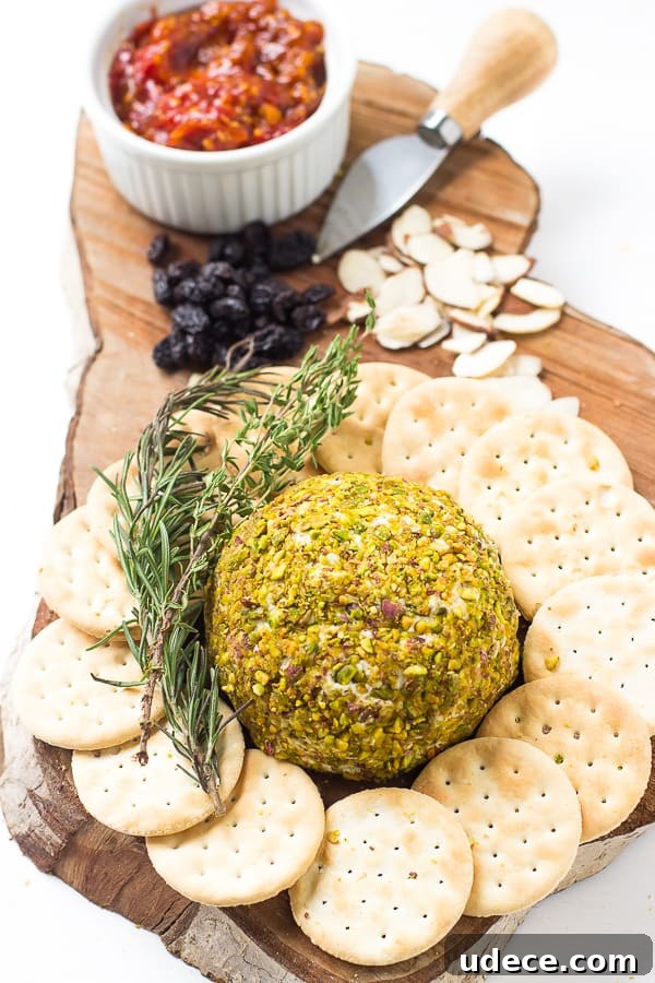 Pistachio-Crusted Vegan Cheese Ball Recipe 3 Top down shot of pistachio crusted vegan cheese ball on a wooden board with crackers.