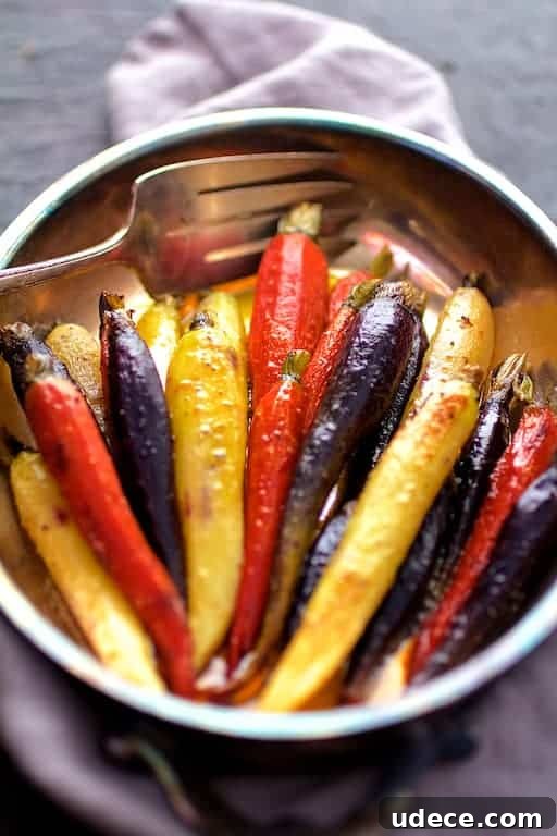 Close-up photo of Curry Roasted Carrots with Honey Browned Butter in serving dish with serving fork on gray napkin.