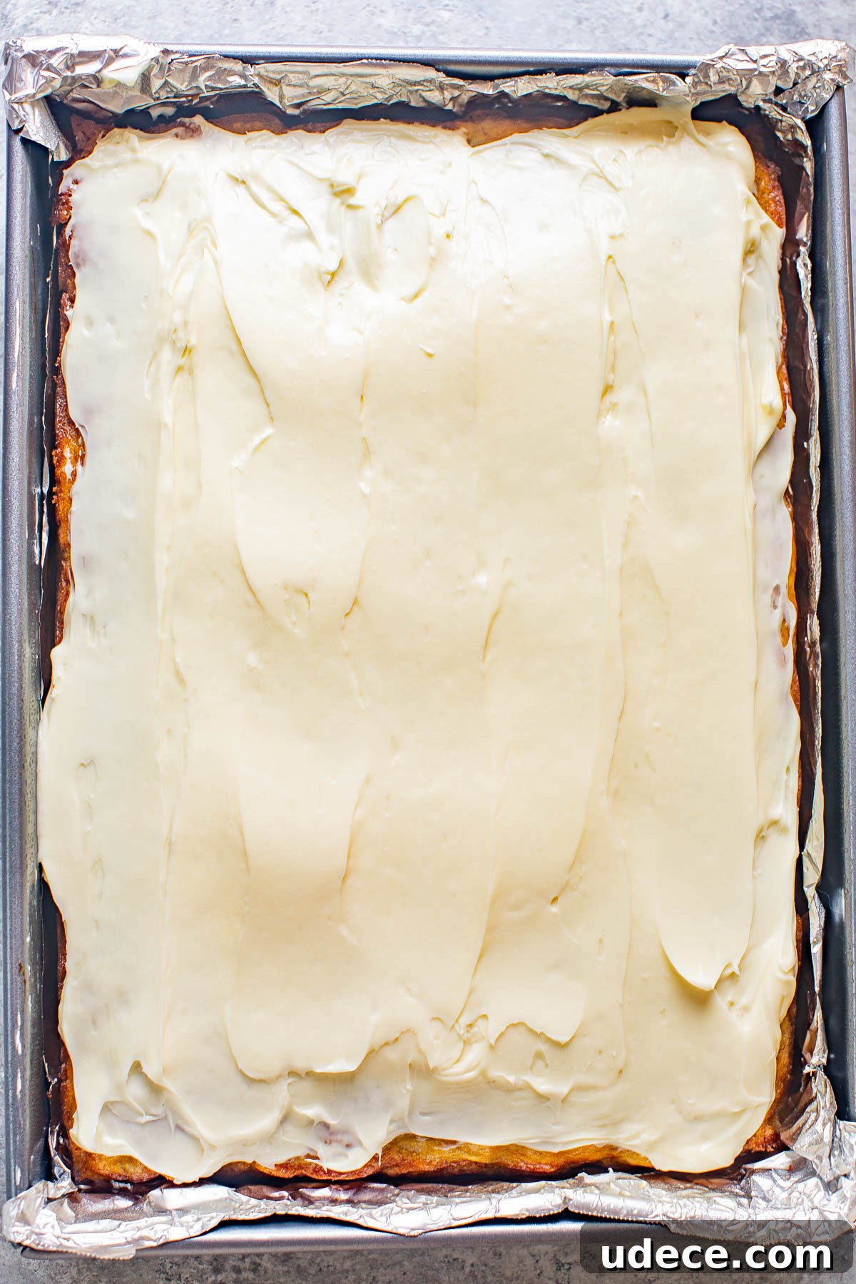 A banana cake topped with cream cheese frosting. 