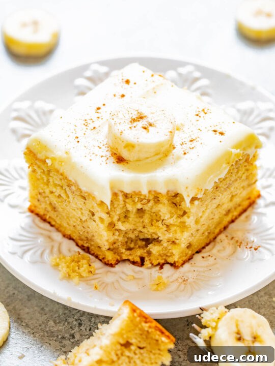 A slice of banana cake with cream cheese frosting with a bite missing.