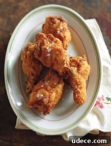 An oval plate with four pieces of Southern fried chicken wings.