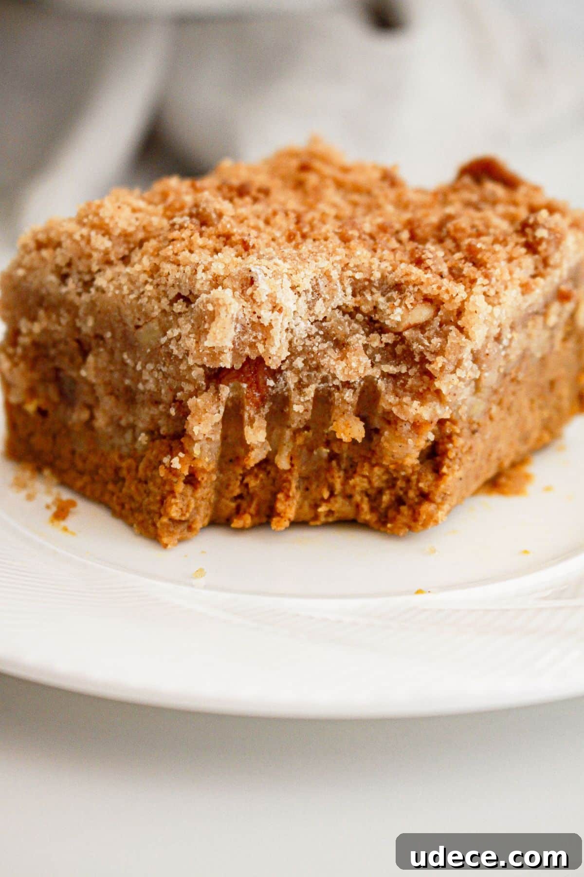 Sllice of pumpkin pie crisp on a plate with a bite misisng.