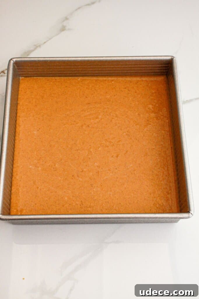 Pumpkin pie filling poured into a metal square baking dish.
