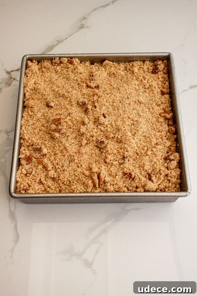 Streusel topping being sprinkled over the top of a baking dish.