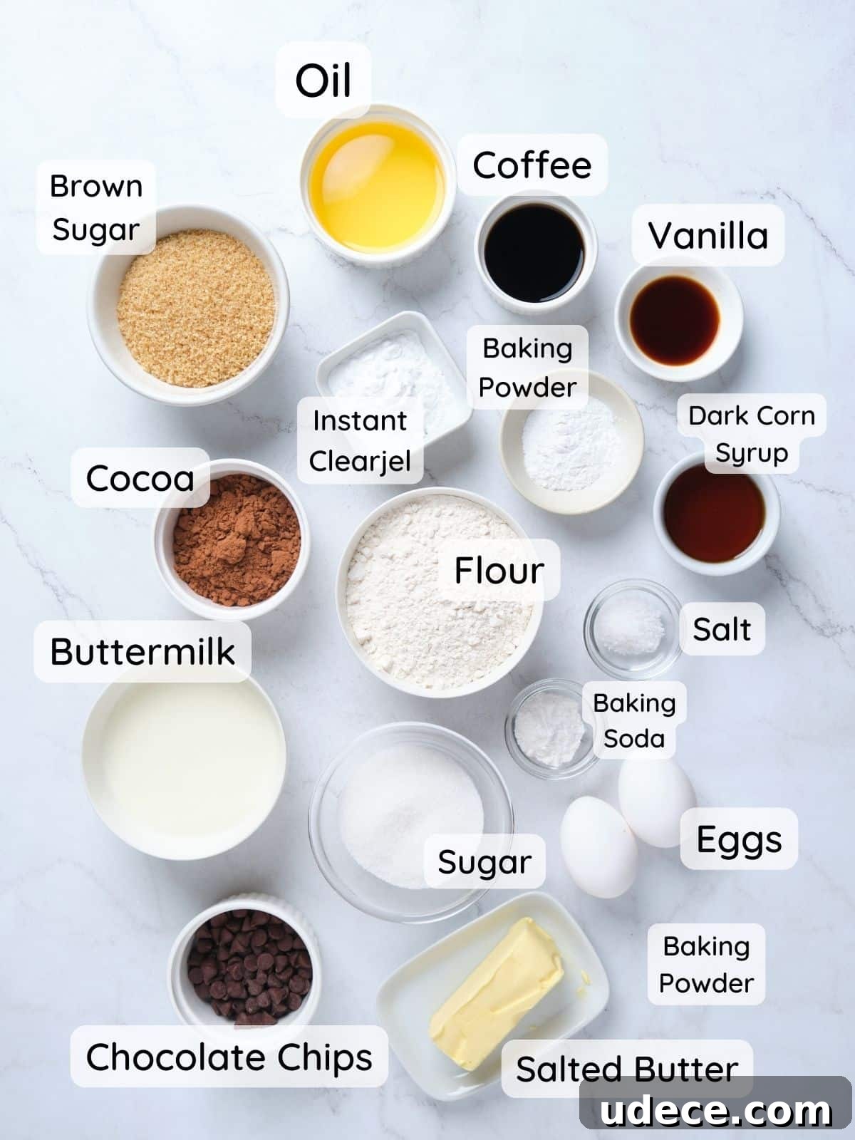 Moist Chocolate Fudge Cake Recipe You’ll Love 4 The chocolate fudge cake ingredients on a table with text overlay of "buttermilk, eggs, vanilla, dark corn syrup, butter, sugar, brown sugar, instant clearjel, baking powder, baking soda, salt, cocoa."