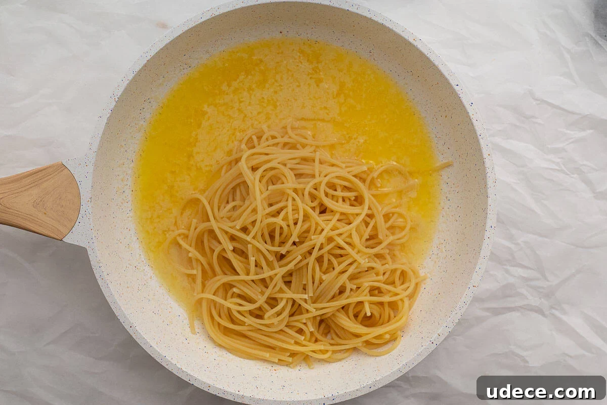 Garlic Butter Pasta with 4 Simple Ingredients 6 pasta being added to garlic sauce in a pan