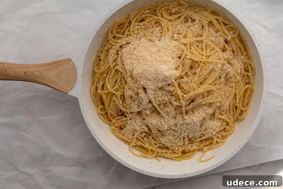 Garlic Butter Pasta with 4 Simple Ingredients 7 parmesan cheese being added to garlic butter pasta in a pan