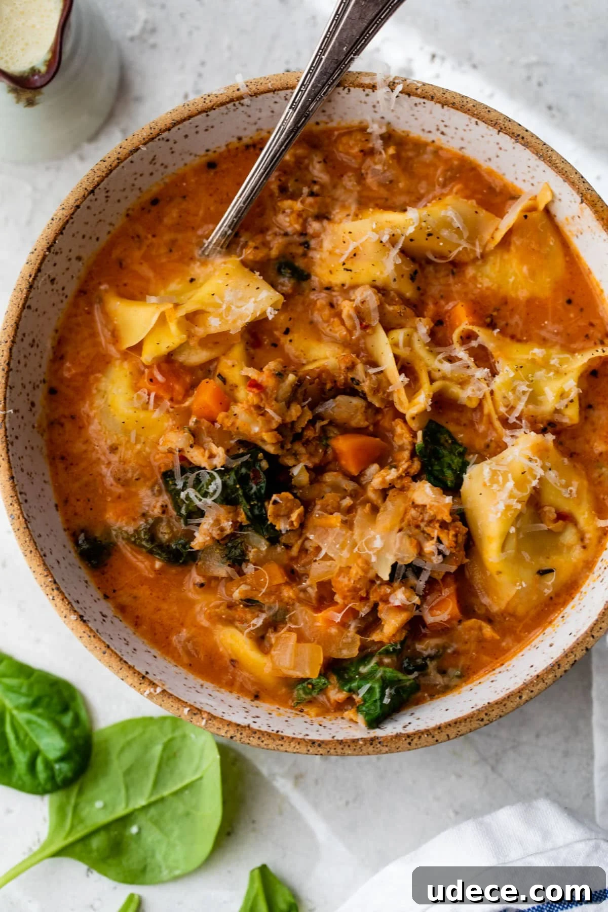 overview of sausage tortellini soup in a bowl with a spoon