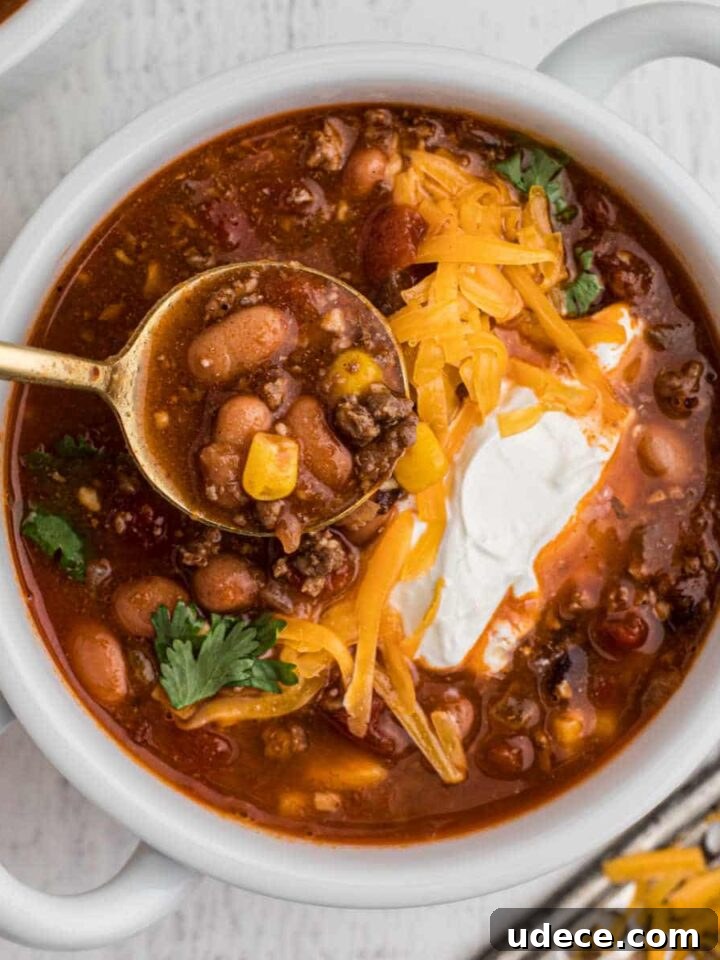 bowl of taco soup with grated cheese and sour cream with a spoon digging in
