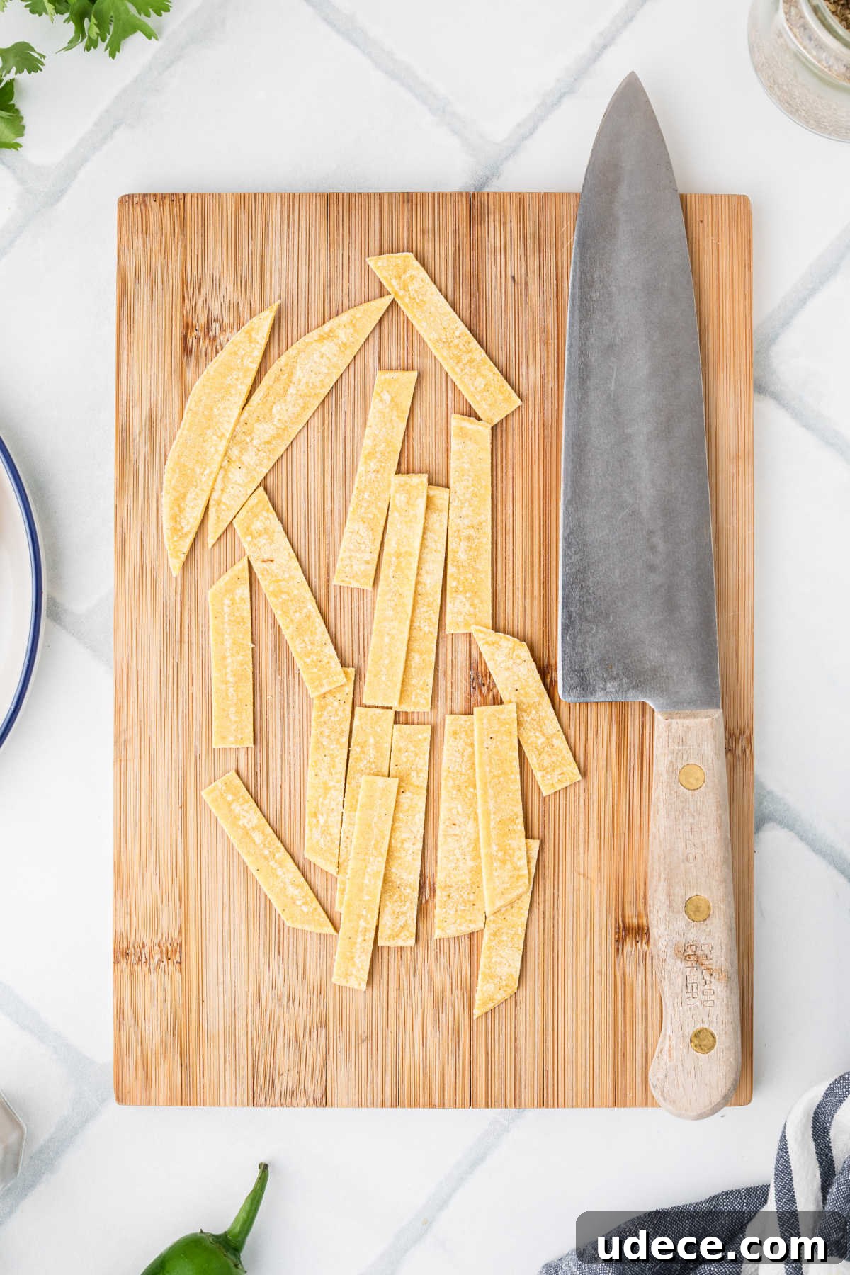 A wooden chopping board with a knife next to some freshly sliced tortilla strips.
