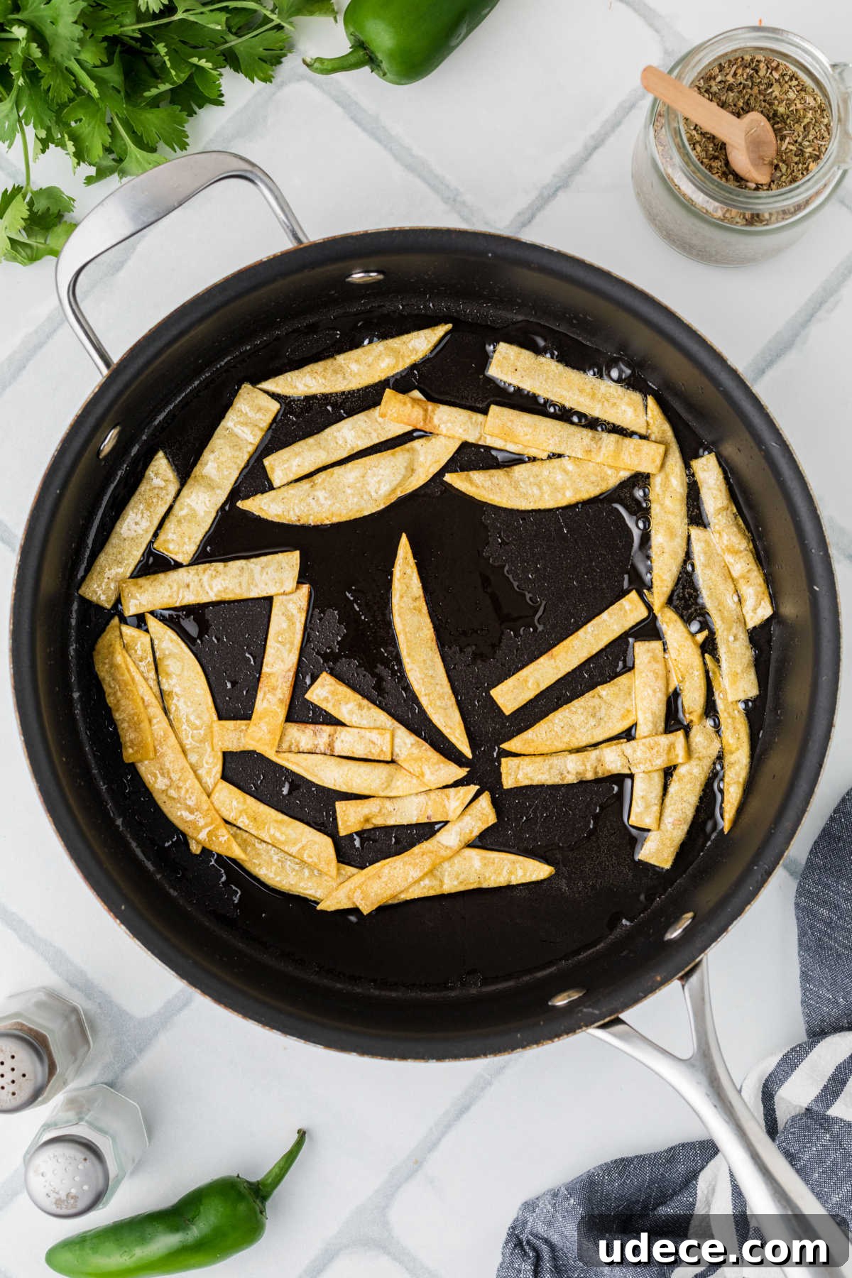 A frying pan, frying some tortilla strips.