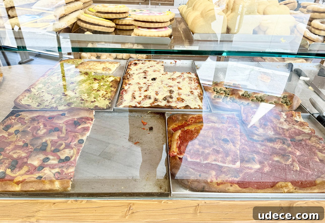 A variety of dressed focaccia breads sold by the slice in a bakery