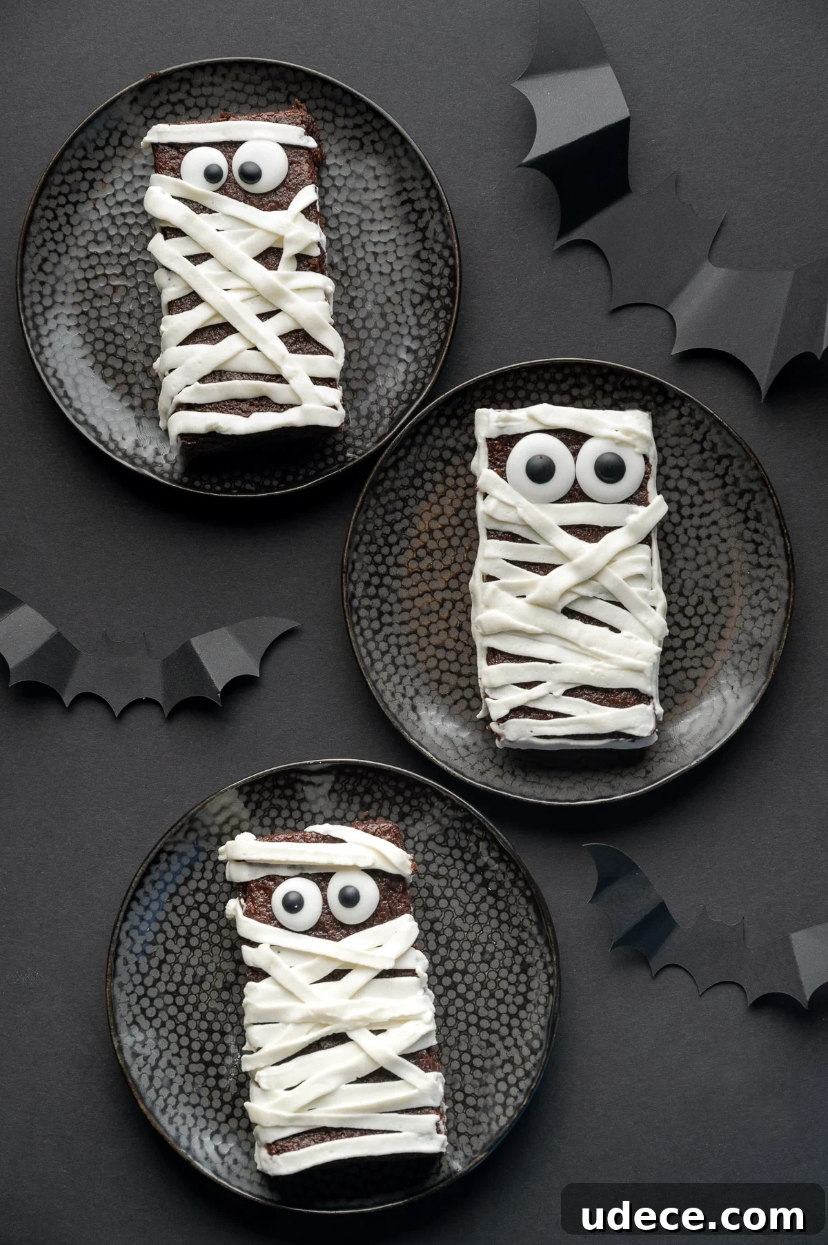 Sugar free brownie with googly eyes and frosting applied in strips to look like bandages on a black background