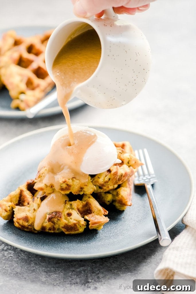hand pouring gravy over poached egg and stuffing waffles
