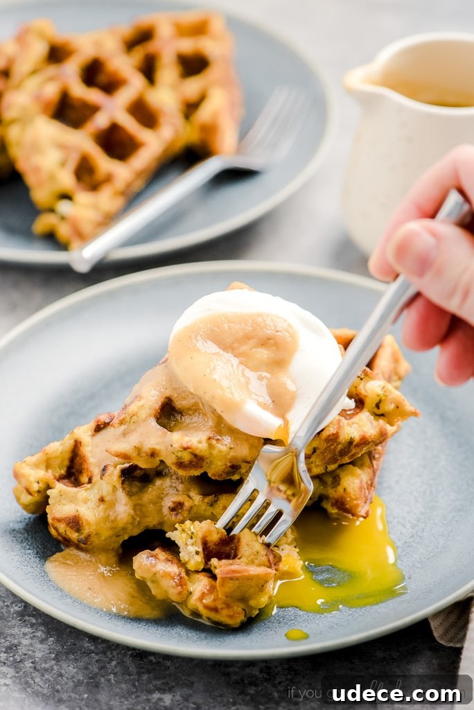 hand holding fork taking bite of leftover stuffing waffles with poached egg and gravy