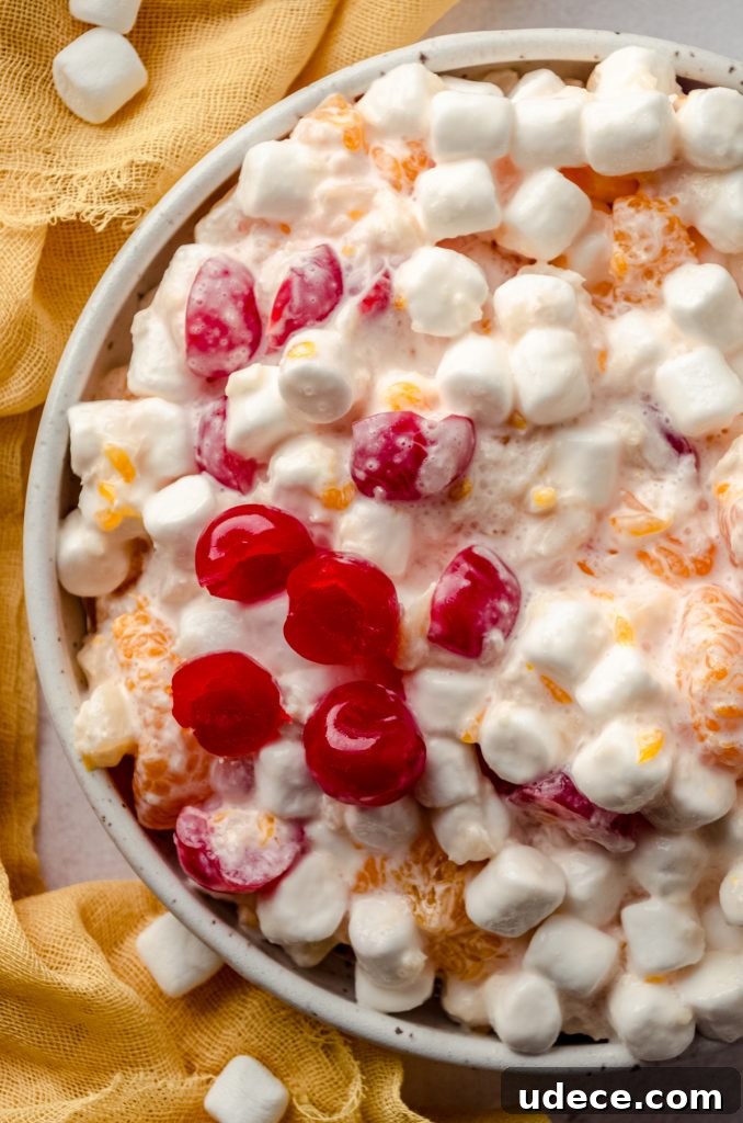 Aerial photo of a bowl of ambrosia salad with a yellow kitchen linen around it.
