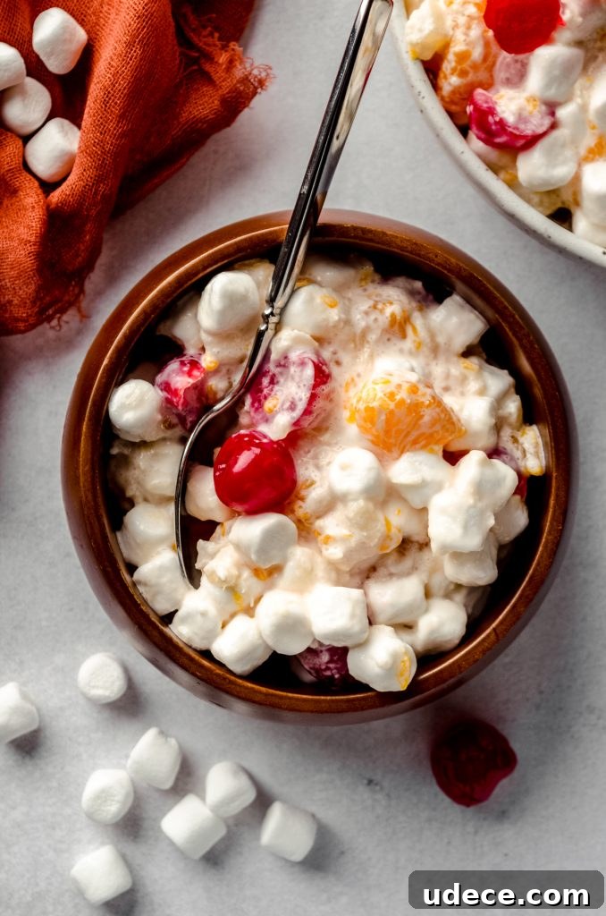 Aerial photo of a small brown wooden bowl filled with ambrosia salad and a spoon.