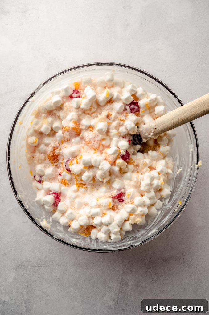 Aerial photo of a bowl of ambrosia salad with a spatula in it.