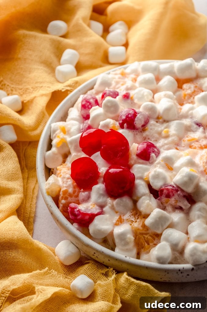 A bowl of ambrosia salad with a yellow kitchen linen in the background.