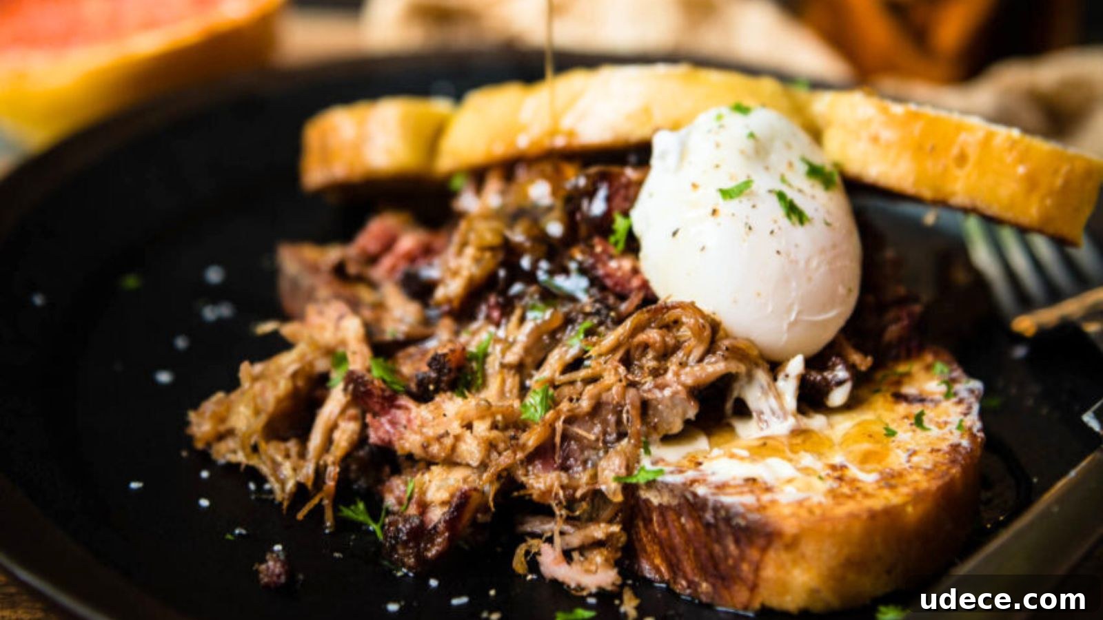 A poached egg rests on shredded beef atop toasted bread, garnished with herbs.