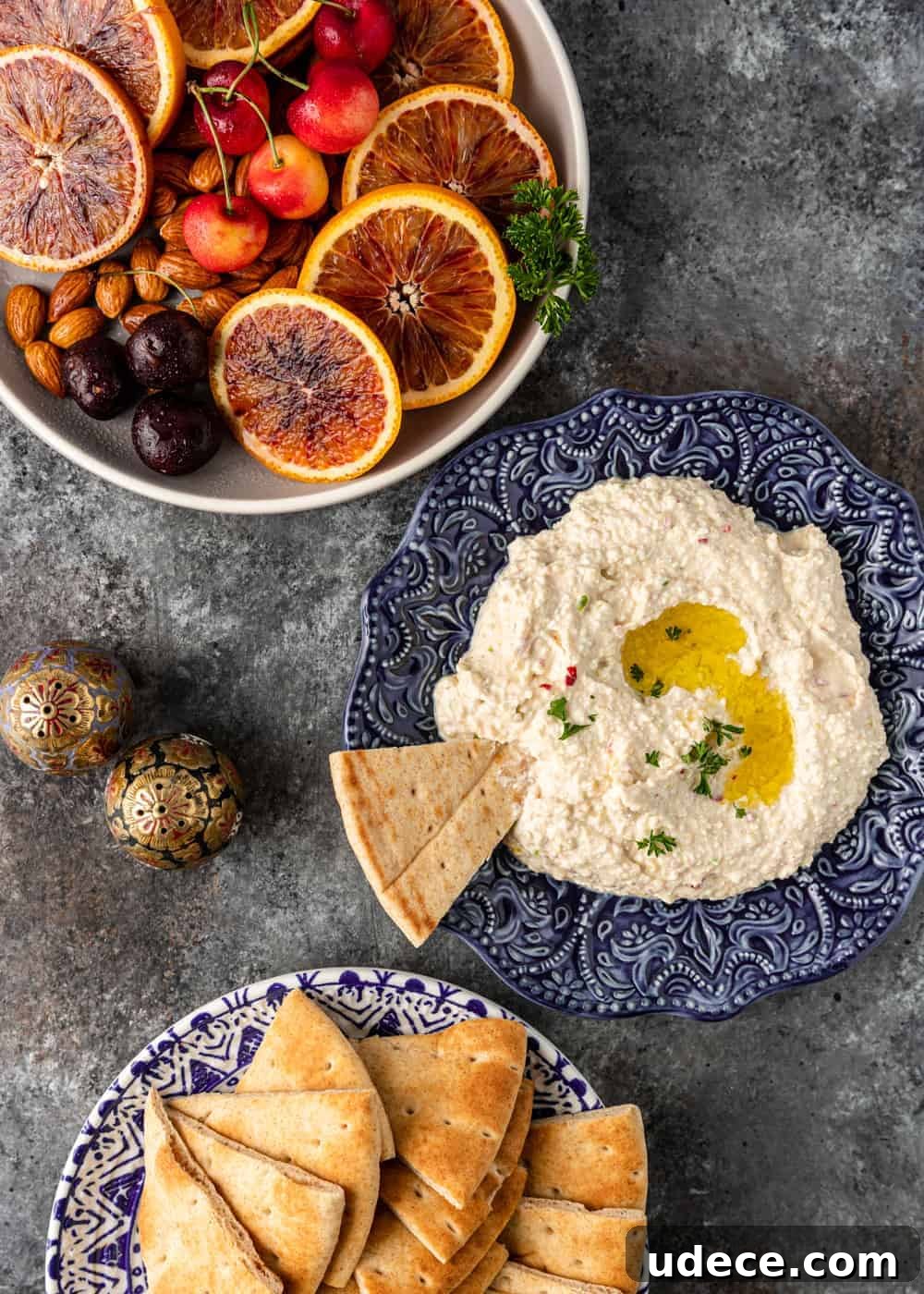 overhead: separate bowls containing fresh fruit, tyrokafteri, and bread triangles